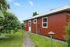 a red cabin with a grass yard next to it at 30320-Odder-Violvej-15 in Odder