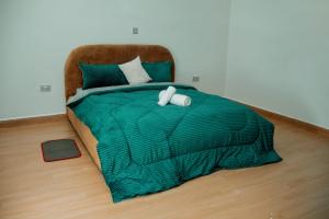 a bed with a green comforter and two towels at Ham Homes in Kampala