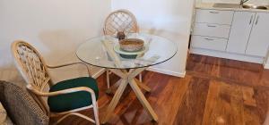 a glass table in a kitchen with two chairs at Mansio Awatere in Snells Beach +3 photos