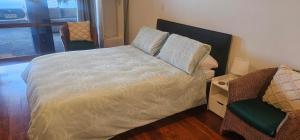 a bed with pillows and a chair in a room at Mansio Awatere in Snells Beach