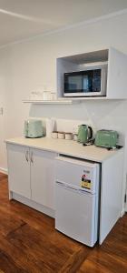 a kitchen with a white counter with a microwave at Mansio Awatere in Snells Beach