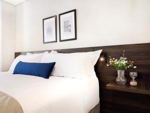 a bedroom with a bed with white sheets and blue pillows at Laureles Selection Suites in Medellín