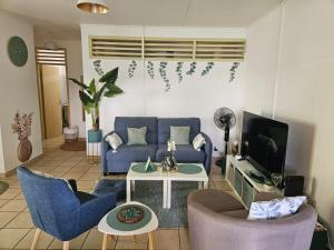 a living room with a blue couch and a tv at Villa dix blue in Kourou