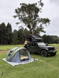 a man standing next to a tent and a jeep at Kauai Explorer Camp Rooftop Camper fully equipped in Anahola