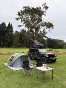 a tent and a jeep parked in a field at Kauai Explorer Camp Rooftop Camper fully equipped in Anahola +6 photos