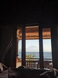 a room with a view of the ocean from a bed at Sandy Beach Villas in Toyapakeh