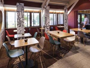 a restaurant with wooden tables and chairs and windows at ibis Montbéliard in Montbéliard +34 photos