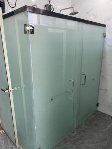 eine Duschabtrennung aus Glas in einem Badezimmer mit Ablagefläche in der Unterkunft Sanibelle Hotel in Coron