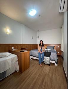 a woman sitting on a bed in a hotel room at Terrazzo Hotel Campos dos Goytacazes in Campos dos Goytacazes +22 photos