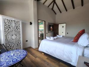 a bedroom with a large white bed and a table at Hotel Boutique El Carmel in Villa de Leyva