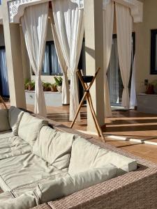 ein Sofa in einem Wohnzimmer mit weißen Vorhängen in der Unterkunft Dar Timi in Ech Chaïbat
