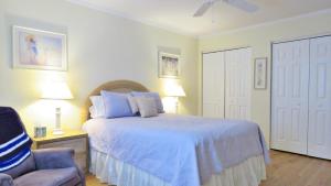 a bedroom with a bed with a blue comforter and a chair at Marilyns Cottage in Cape May