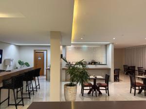 a restaurant with tables and chairs and a kitchen at Izzy Hotel in Uberlândia