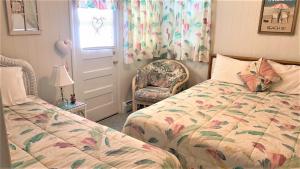 a bedroom with two beds and a chair and a window at Rulons Cape May Diamond, 1St in Cape May