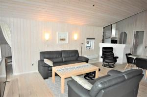 a living room with a leather couch and a table at 30835-Ulfborg-Kornblomstvej-409 in Ulfborg
