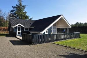 a small house with a black roof and a fence at 30835-Ulfborg-Kornblomstvej-409 in Ulfborg