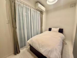 a small bedroom with a white bed and a window at Villa Monica 30sec in Noritake-Shinmachi