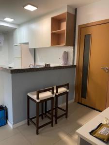 a kitchen with two stools in front of a counter at Garden em Guarajuba in Tareco