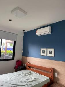a bedroom with a bed and a blue wall at Garden em Guarajuba in Tareco