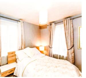 a bedroom with a bed and two windows at Elegant 2 BR Apartment in Historic Cambridge in Papworth Everard