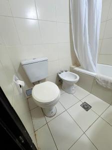 a white bathroom with a toilet and a shower at HOTEL APOLO NEUQUEN in Neuquén