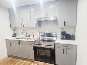 a kitchen with white cabinets and a stove top oven at Snug 2 bedroom sleeps 5-Netflix in Edmonton