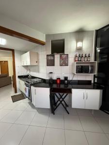 a kitchen with white cabinets and a black counter top at Apartamento moderno - Amazonas Flat in Manaus