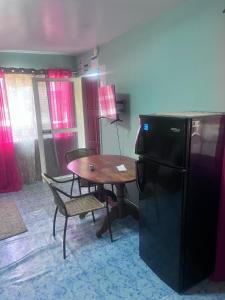 a kitchen with a table and a black refrigerator at Garden Lodge Hotel in Placencia