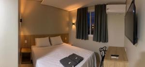 a small bedroom with a bed and a television at Izzy Hotel in Uberlândia