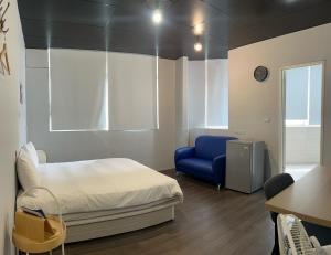 a bedroom with a bed and a blue chair at 好客輕旅 in Donggang