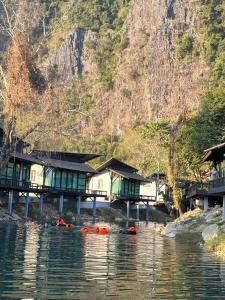 a group of houses on the water with kayaks at Oasis VangVieng Resort & Cafe in Ban Naka