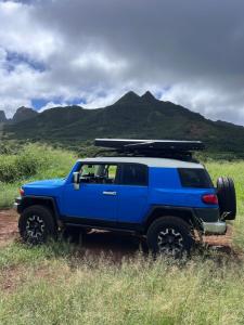 a blue jeep with a surfboard on top of it at Kauai Adventure fully equipped FJ Cruiser Rooftop Camper in Anahola