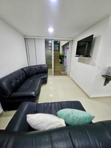 a living room with a black leather couch and a flat screen tv at Raíz Serena in El Retiro