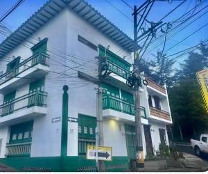 a white and green building with a car parked in front at Raíz Serena in El Retiro