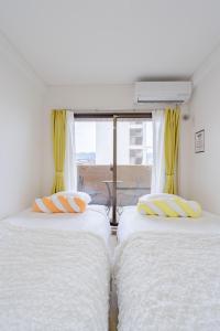 two twin beds in a room with a window at アンドステイ屋形町306 in Kyoto