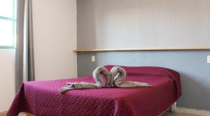 a bed with a pair of animal towels on it at Real Hotel y Alojamientos in Pachuca de Soto