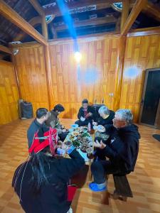 a group of people sitting around a table eating food at Lý Gún homestay in Quang Ba