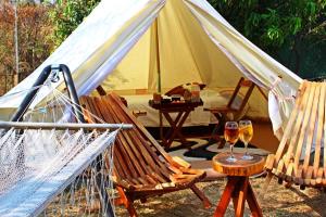 a tent with two glasses of wine and two chairs at Glamping Wellness Pet Friendly El Secreto in Tepoztlán