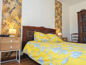 a bedroom with a bed with a yellow comforter at Maison avec parking - 7 pers. - FR-1-591-784 in Éguzon-Chantôme