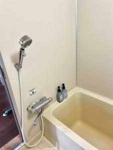 a bath tub with a shower and a sink at Nomad Gala Otaru in Otaru +35 photos