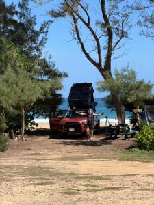 a man is standing next to a red truck with its roof up at Kauai your way Rooftop Camper fully equipped SUV in Anahola +9 photos