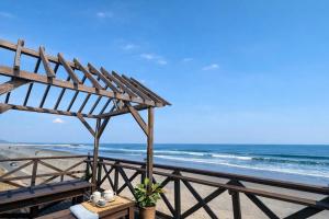 a view of the beach with a bench and the ocean at Aloha Beach Deck , Oceanfront, Stunning Sunrises, BBQ, Karaoke in Hokota