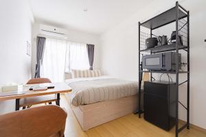 a bedroom with a bed and a table and a desk at アンドステイ屋形町507 in Kyoto