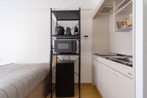 a small bedroom with a bed and a shelf with a television at アンドステイ屋形町507 in Kyoto