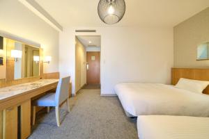 a hotel room with two beds and a desk and a mirror at Hotel Global View Urawa in Saitama