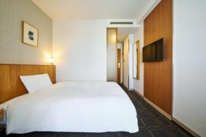a bedroom with a white bed and a flat screen tv at Hotel Global View Urawa in Saitama