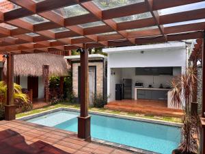 an outdoor kitchen and swimming pool with a pergola at Villa lumbung sari in Cemagi