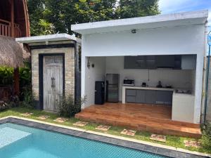 a kitchen and a swimming pool next to a house at Villa lumbung sari in Cemagi