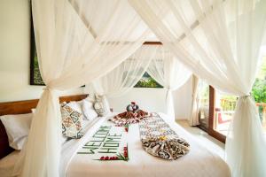 a bedroom with a white bed with white curtains at Akamana Villa Ubud in Ubud +18 photos