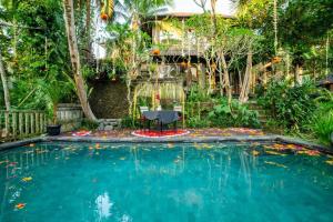 a pool with a table and a chair in a garden at Akamana Villa Ubud in Ubud